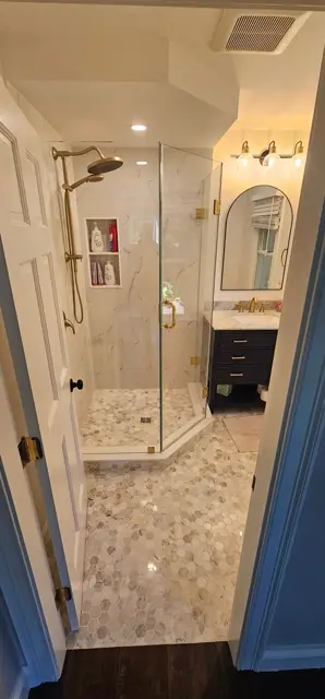 Marble bathroom with brass fixtures, a glass corner shower and a dark wood vanity