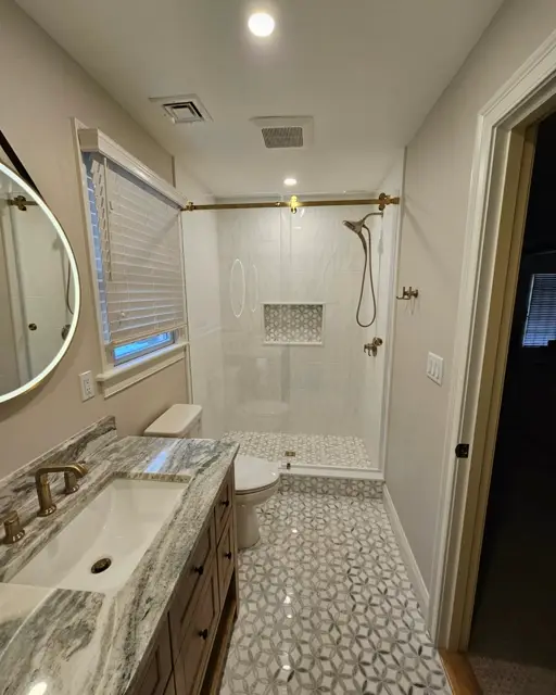 Walk-in shower with a mosaic niche and bronze fixtures beside a marble hex floor