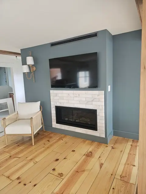 Fireplace with a marble subway tile surround against a deep blue accent wall