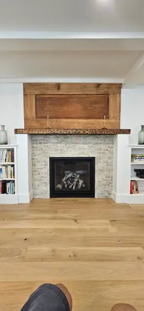 Fireplace with a rustic wood mantel and a brick-look tile surround