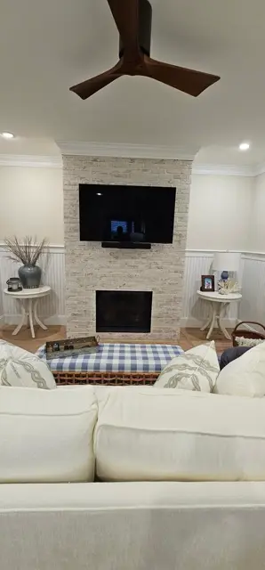 Living room fireplace faced in whitewashed stone with a wood mantel