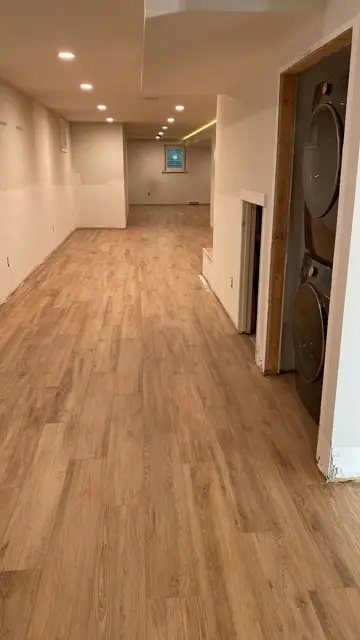 Wide-plank wood-look tile flooring through an open basement hallway