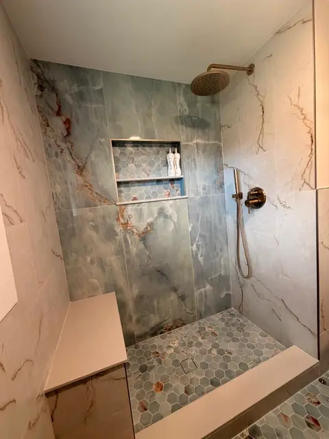 Marble shower with a built-in bench and brushed gold fixtures