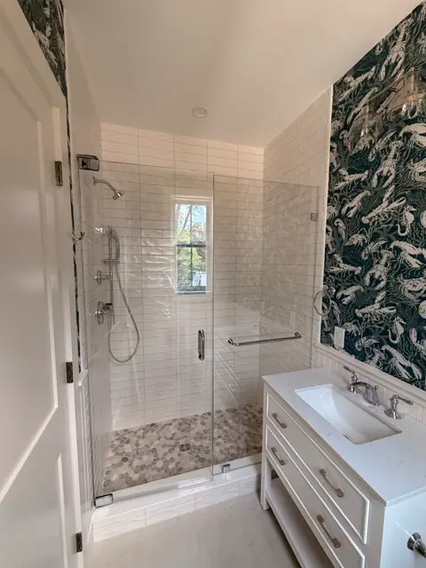 Walk-in shower with white subway tile and a botanical accent wall
