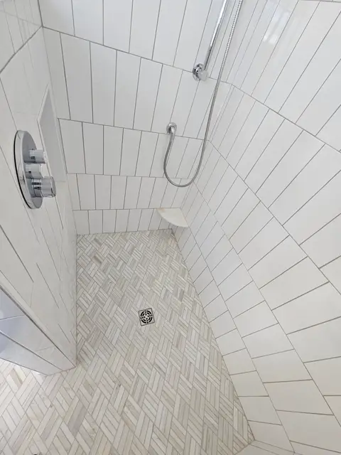 Bright walk-in shower finished in white vertical-plank tile