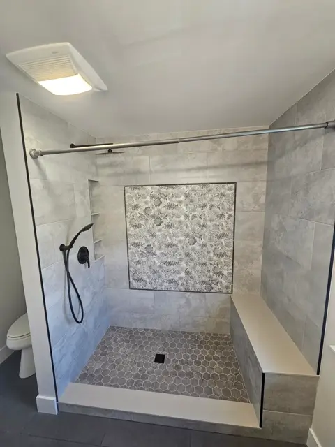 Shower corner with a built-in bench and a herringbone tile floor