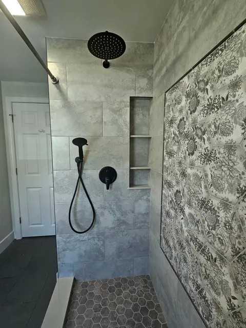 Walk-in shower with a bold floral accent wall and matte black fixtures