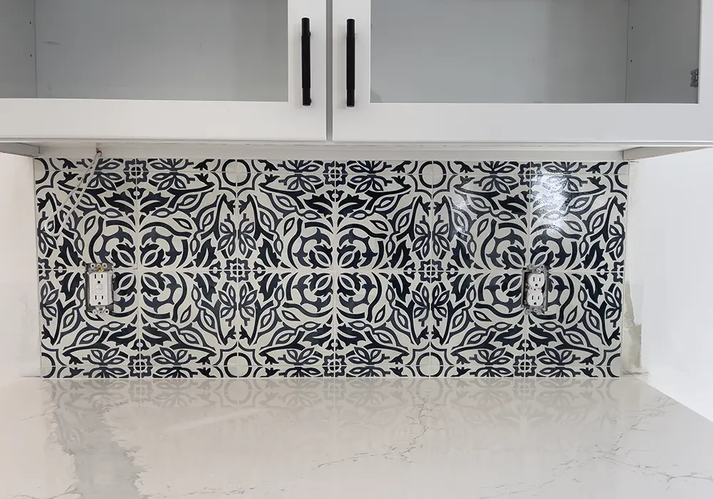 Decorative black and white backsplash under white cabinets